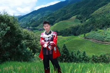 外出旅行体验红色民族服装，抱臂站在梯田前