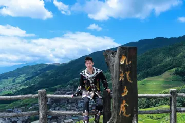 外出旅行体验黑色民族服装，站在木质观景标牌旁