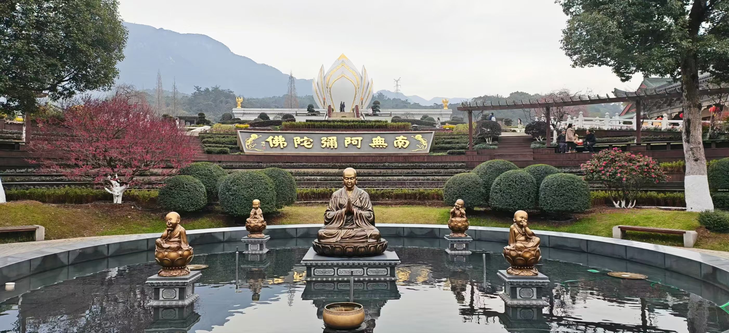 寺院庭院里的水池、雕像、花树与远处的山